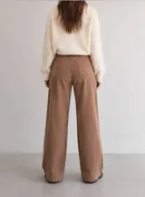 Pantalón de pana color tostado con corte wide leg y tiro alto. Presenta diseño clásico de cinco bolsillos, cierre frontal con botón y una caída recta y amplia.