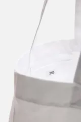 Bolso tipo shopper blanco de tela con asas de hombro. Estampado frontal con texto "Athletic Sports Club", una palmera y la frase "Embrace the lifestyle" con el año "Est. 1975".