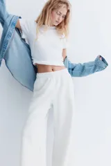 Pantalón de jogging de corte ancho y tiro alto, color gris melange, confeccionado en tejido de felpa con interior cepillado suave. Posee cintura elástica fruncida con cordón de ajuste oculto, bolsillos laterales y un bolsillo trasero abierto.