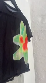 Top negro de microtul con estampado de orquídeas verdes.