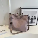 Bolso tipo tote y shopper de color negro, confeccionado en poliéster con amplio espacio interior, doble asa de mano y correa larga ajustable para llevar al hombro o cruzado.
