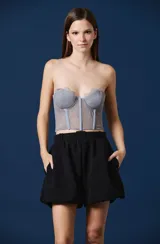 Top tipo corset de encaje negro con escote strapless y copas estructuradas. Presenta detalles de encaje con bordes festoneados y paneles transparentes en el torso.