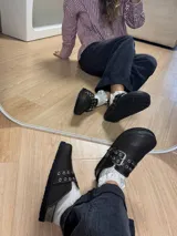 Zuecos de cuero color marrón oscuro con hebilla plateada y detalles de tachas.