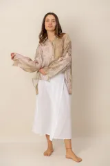 Camisa beige de manga larga con estampado botánico y floral, confeccionada en tejido liviano y traslúcido, con cuello camisero y cierre frontal de botones.