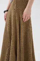 Falda larga de punto color mostaza, con cortes asimétricos, distintos puntos texturizados, ruedo irregular y pretina elástica con detalles en tono contrastante.