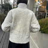 Campera de cuero ovino color tostado con interior de piel sintética blanca. Tiene cuello alto con solapas y cierre frontal con cremallera.