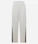 Pantalón deportivo de corte oversized estilo college, confeccionado en microfibra color crema con rayas laterales contrastantes en color marrón. Presenta cintura fija, bolsillos funcionales y frisos frontales.