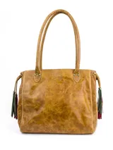 Cartera Hush Puppies de cuero color tostado, tipo shopper, con doble asa de hombro y detalles de flecos colgantes en los laterales. Presenta costuras visibles y el logo grabado en el frente.