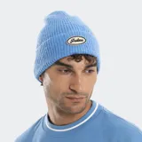 Gorro tipo beanie tejido en punto acanalado, color celeste, con parche ovalado en el frente que presenta el logo de la marca bordado.