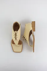 Sandalias de cuero color beige con diseño de ojota acordonada en el empeine, puntera cuadrada y taco bajo cuadrado.