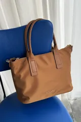 Cartera tipo shopper color negro, de diseño estructurado con doble asa de mano y cierre superior. Presenta sutil grabado de la marca en la parte inferior frontal.
