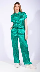 Pantalón de satén verde con estampado floral, corte holgado y cintura con cordón ajustable.