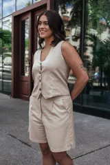 Short color beige de tiro alto con pinzas delanteras, bolsillos laterales y cierre frontal con botón y cremallera.