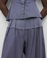 Pantalón ancho color gris azulado, de lino y algodón, con pinzas delanteras, canesú en delantero y espalda en tejido a contraste, cinturilla elástica en espalda y bolsillos laterales.