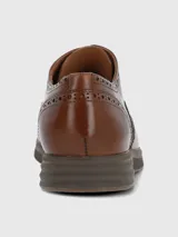 Zapato tipo oxford de cuero color marrón con diseño brogue, cordones al tono y suela de goma tipo deportiva.