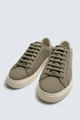 Zapatilla de cordones color negro con parte superior lisa, horma redonda y forro interior a contraste. Suela de goma color crema con ligera textura y detalle en el talón color crema.