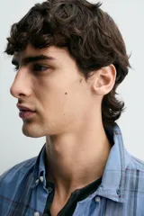 Camisa de corte regular fit confeccionada en tejido ligero de algodón, con estampado de cuadros en tonos azules y grises. Presenta cuello abotonado, manga larga con puños abotonados, bolsillo plastrón en el pecho y cierre frontal de botones.