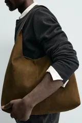 Bolso de hombro liso color verde militar, con compartimento principal con cierre de imán y un bolsillo interior con cremallera. Tiene un asa de hombro.