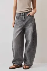 Jeans de corte barrel en tono gris deslavado, con diseño amplio y tachas decorativas a lo largo de las costuras laterales y los bolsillos delanteros.
