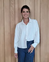 Camisa de color arena con cuello clásico, cierre frontal de botones y mangas largas abullonadas con puños anchos.