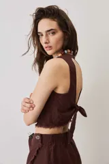Blusa cropped color chocolate, de silueta suelta y cuello redondo, con terminación de bordes deshilachados.