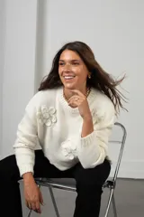 Buzo de punto color blanco, de corte holgado y cuello redondo, con diseño de flores aplicadas con detalles de mostacillas bordadas.