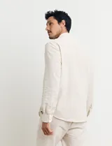 Camisa de cuello mao y manga larga, confeccionada en una mezcla de lino y algodón. Presenta un diseño de corte recto con botones en tono natural y un bolsillo pequeño en el pecho.
