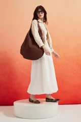 Cartera tipo hobo de gran tamaño en color marrón, con diseño minimalista y correa trenzada en tonos oscuros.