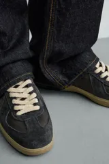 Zapatilla de estilo retro con diseño de paneles en cuero y serraje, cordones en tono crudo y suela de goma a contraste.