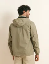 Campera impermeable gris con capucha, cierre frontal y bolsillos laterales con cremallera.
