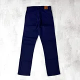 Pantalón jean azul marino, de corte recto, con bolsillos laterales y traseros. Se ajusta a la cintura con cinturón de cuero marrón.