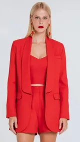 Blazer de sastrería color rosado con diseño estructurado, cuello solapa redondeado y cierre frontal con broche metálico. Cuenta con bolsillos laterales con solapa y un bolsillo superior decorativo.