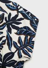 Mono largo de lino y viscosa con estampado de hojas en tonos azul y negro. Tiene cuello de pico, manga corta, cinturón con hebilla, dos bolsillos laterales y cierre de botón en la parte posterior.