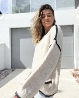 Sweater de punto en color crudo con detalles de costuras y bordes en color negro. Presenta un diseño de corte holgado, cuello redondo y mangas largas con puños acanalados.