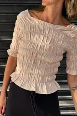 Remera negra de algodón con textura fruncida en todo el cuerpo y mangas cortas con terminación de volado.