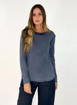 Remera de manga larga color azul, con cuello redondo adornado con un detalle de textura desflecada o peluda en el borde.