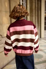 Buzo tejido de punto con diseño de rayas horizontales en tonos rosado, marrón y crema. Presenta cuello redondo alto y puños acanalados.