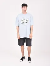 Remera blanca de corte oversized con estampado frontal de letras en color naranja y negro.