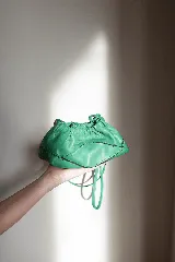 Cartera sobre de cuero 100% color verde, de diseño fruncido con cierre superior y etiqueta colgante en combo.