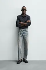 Jeans de corte recto y tiro medio confeccionados en denim de algodón con efecto lavado, diseño de cinco bolsillos y cierre frontal con cremallera y botón.