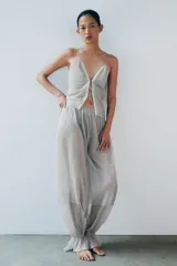Pantalón abombacho semitransparente de tejido de encaje suave color gris, con tiro medio, cintura elástica y diseño con calados y volantes en los tobillos.