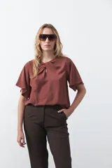 Top negro de manga corta con detalle de nudo en el escote y abertura tipo gota. Presenta una silueta relajada y textura sutil en la tela.