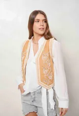 Chaleco de denim color camel con bordados florales en blanco y aplicaciones de perlas en el frente.