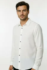 Camisa de poliéster color blanco con textura granulada, cuello camisero, botones oscuros y diseño de manga larga con puños.