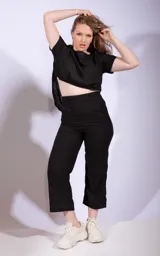 Mono negro de dos piezas, compuesto por una remera de mangas cortas y un pantalón capri de tiro alto.