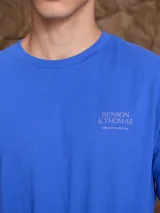 Remera de manga corta color azul con estampa artística en la espalda que representa una fachada de edificio con sombras.