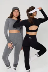 Conjunto deportivo compuesto por un top de manga larga con cuello redondo y calzas de tiro alto, ambos en color negro con detalles de textura en tejido seamless.