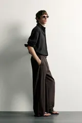 Pantalón barrel fit de corte ancho color marrón, confeccionado en mezcla de algodón y lino. Presenta bolsillos frontales, bolsillos traseros de vivo y cierre frontal con cremallera y botón.