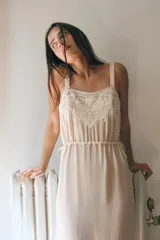 Vestido midi semitransparente de viscosa con escote recto y tirantes finos. Presenta bordados florales a contraste en el pecho y detalle de lazadas ajustables en los laterales.