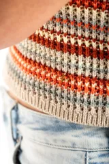 Top tejido de punto con diseño a rayas horizontales en tonos tierra, naranja y crema. Presenta un corte al cuerpo, escote halter y breteles finos.